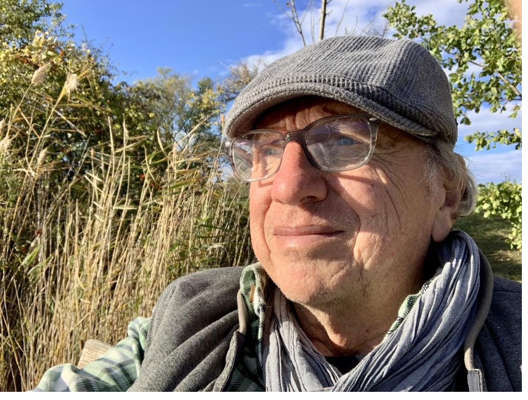 Portrait of Franz Riess outdoors, wearing a flat cap and glasses